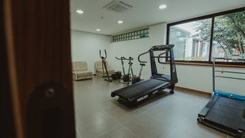 A gym with a treadmill, stationary bikes, and a weight bench.