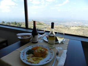 A table with a meal, two wine bottles, and a view of a landscape through a window. - Albergaria Senhora do Espinheiro (Seia)