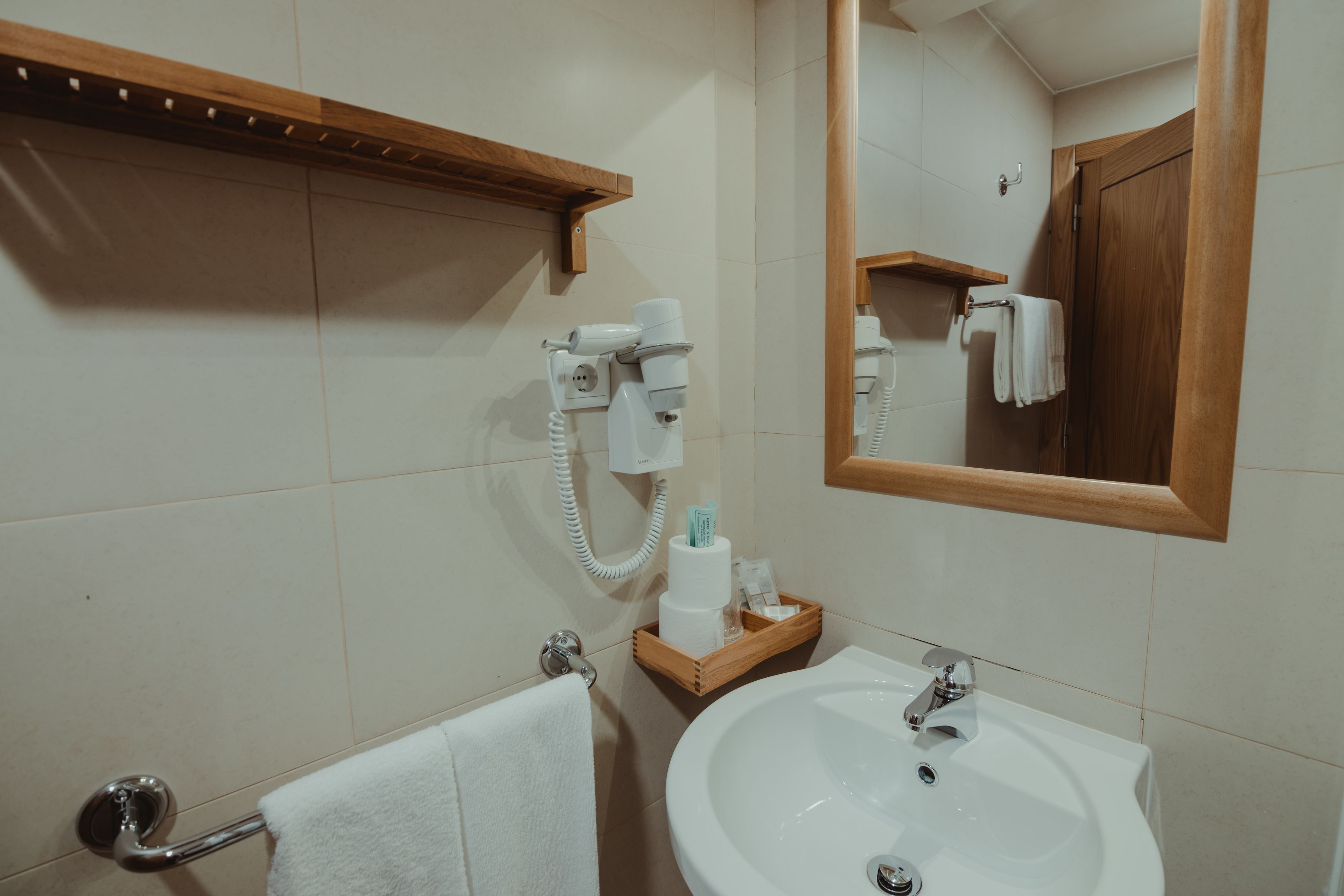 A bathroom with a sink, mirror, towel rack, and hairdryer.