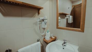A bathroom with a sink, mirror, towel rack, and hairdryer.