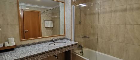 Un baño con encimera de granito, un lavabo, un espejo, una ducha y una puerta.
