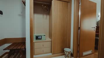 Una habitación con un armario de madera, una mesita con un radio y un cubo de basura.