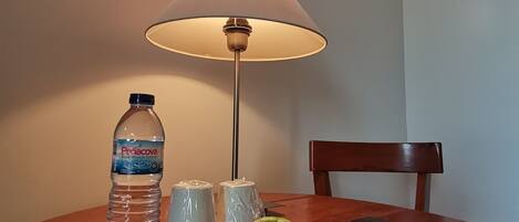 Una mesa con un plato de manzanas, una botella de agua y una lámpara.