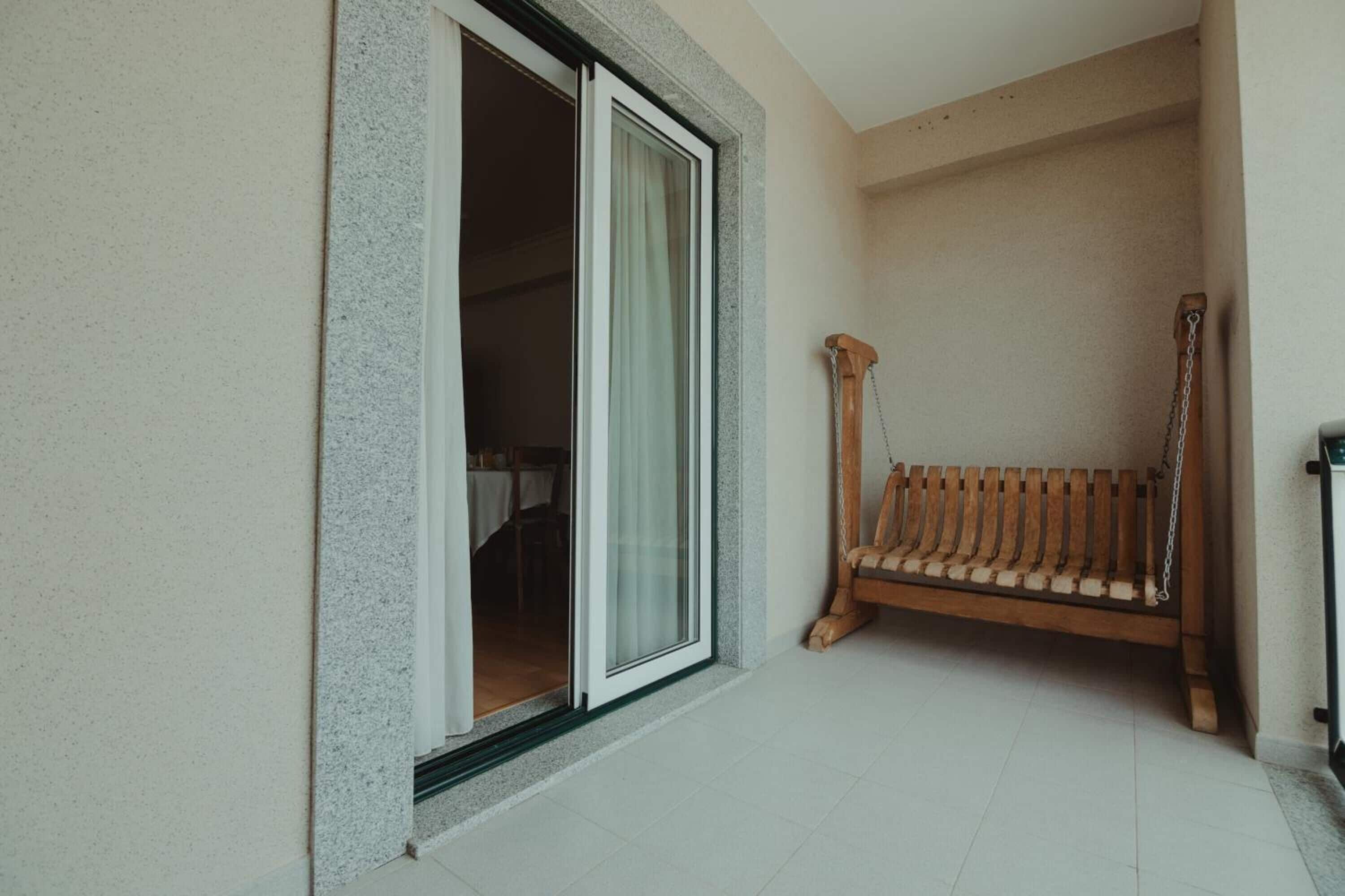 A room with a sliding glass door leading to a dining area, a wooden bench, and a small table.
