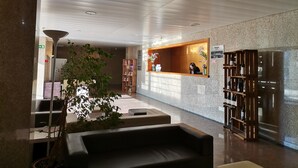 Un hall d’entrée avec un comptoir de réception, un espace salon et un présentoir à vins.