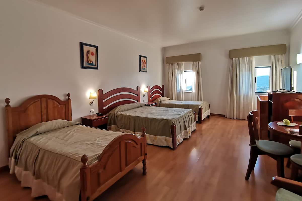 Ein Hotelzimmer mit zwei Holzbett, einem Schreibtisch mit Stuhl und einem Fernseher.
