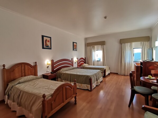 A hotel room with two wooden beds, a desk with a chair, and a TV.