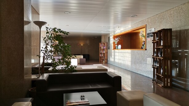 Un hall d’entrée moderne comprenant un comptoir d’accueil, un espace salon et une bibliothèque.