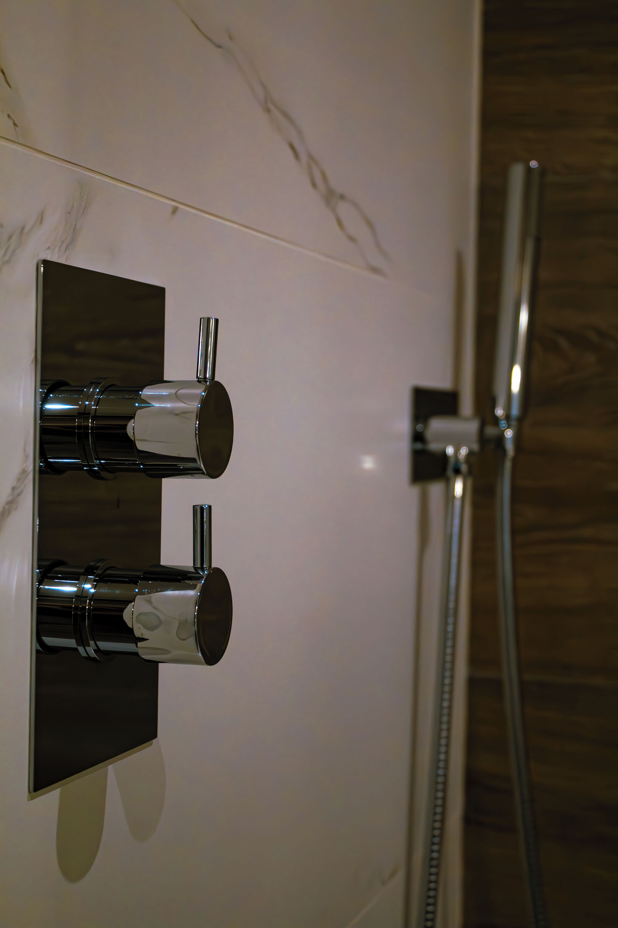A modern bathroom with a wall-mounted shower and two towel dispensers.