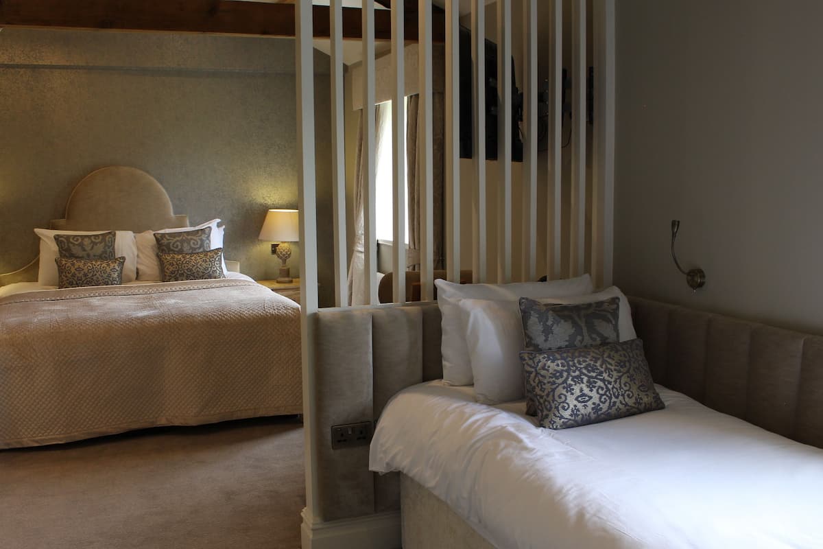 A hotel room with two beds, each with patterned pillows and a bedside table with a lamp.