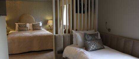 A hotel room with two beds, each with patterned pillows and a bedside table with a lamp.