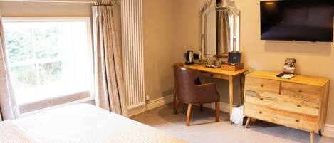 A bedroom with a bed, a desk, a chair, a dresser, a mirror, and a TV.