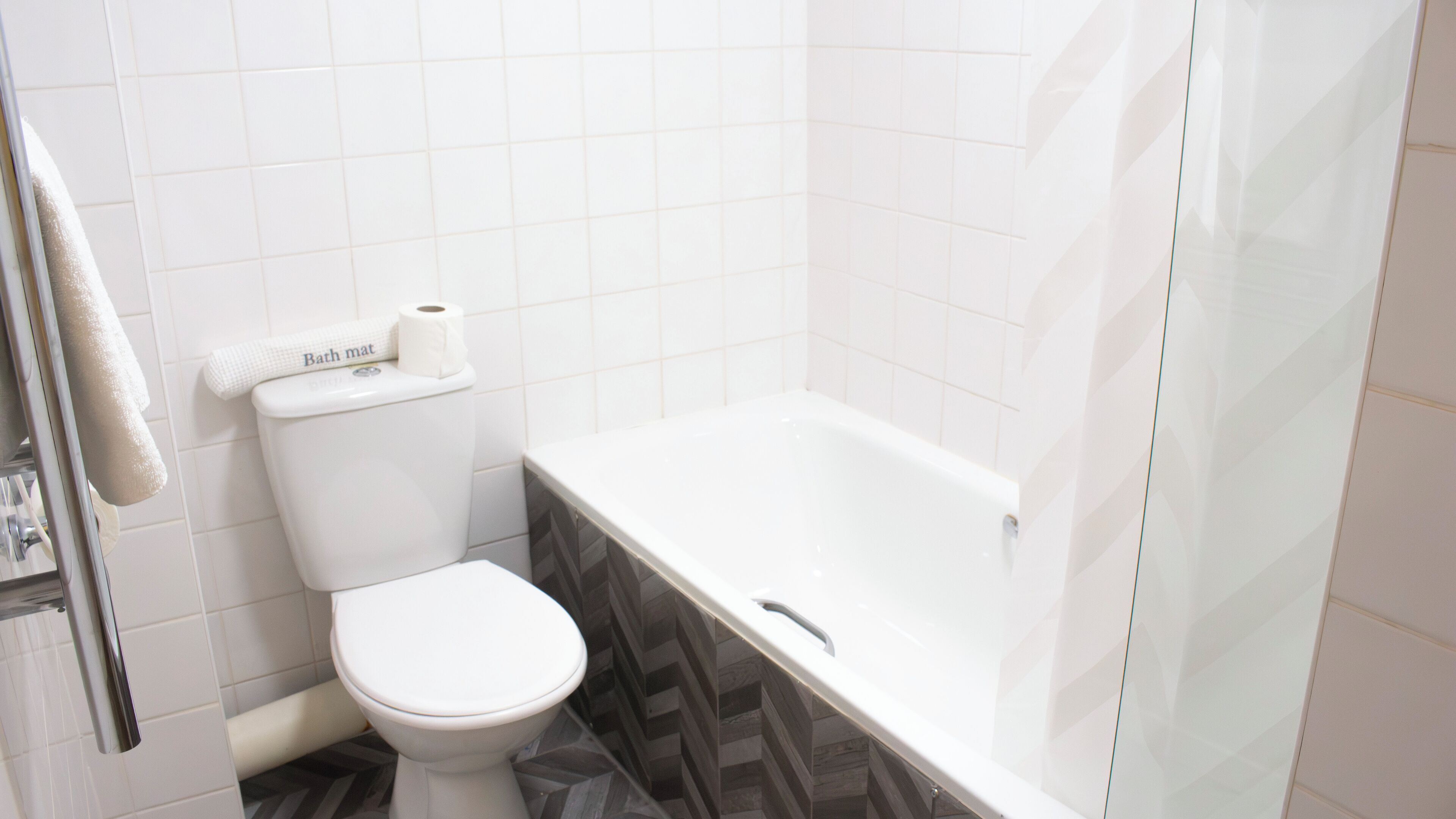 Ein Badezimmer mit Toilette, Badematte und Badewanne.