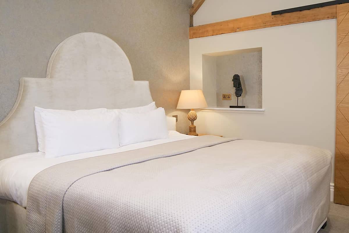A bed with a headboard, a bedside lamp, and a framed picture on the wall.