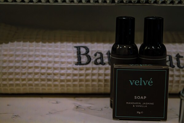 A bottle of Velvé soap and a box on a surface with a towel in the background. - Manor House Hotel (Bishop Auckland)