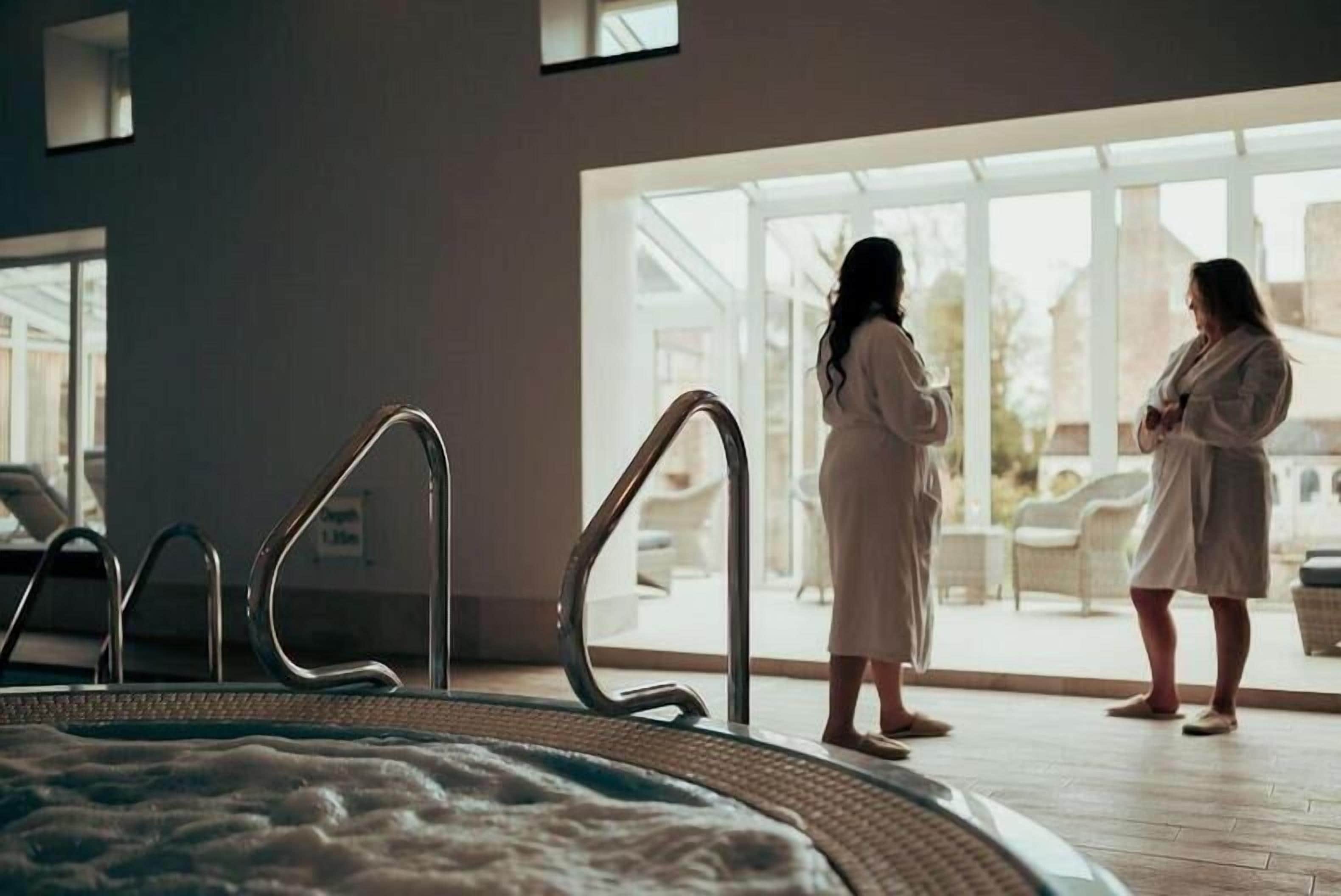 A spa area with a hot tub, a glass door leading outside, and a view of the outdoors.