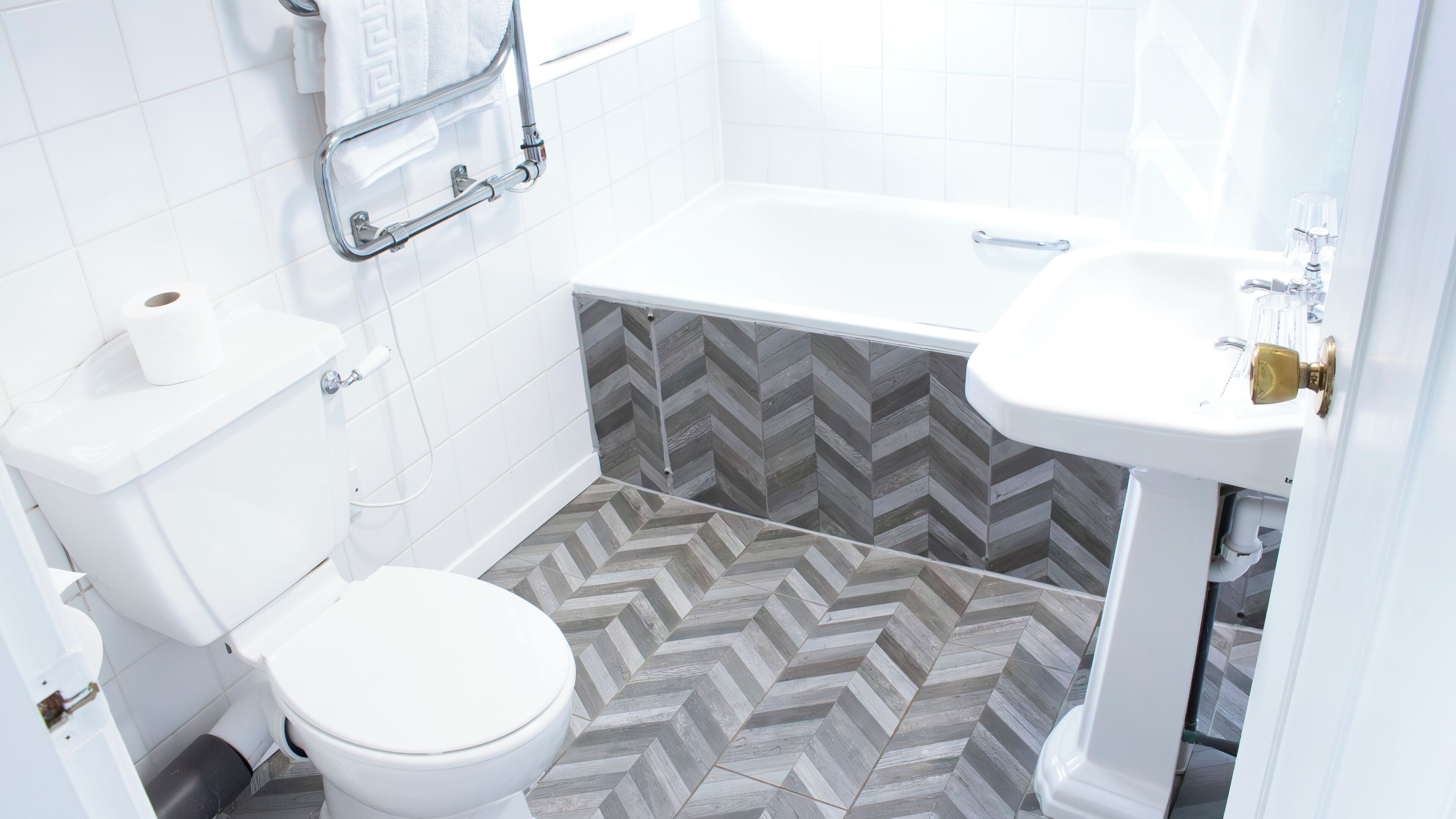 Une salle de bain avec des toilettes blanches, un lavabo blanc et une baignoire.