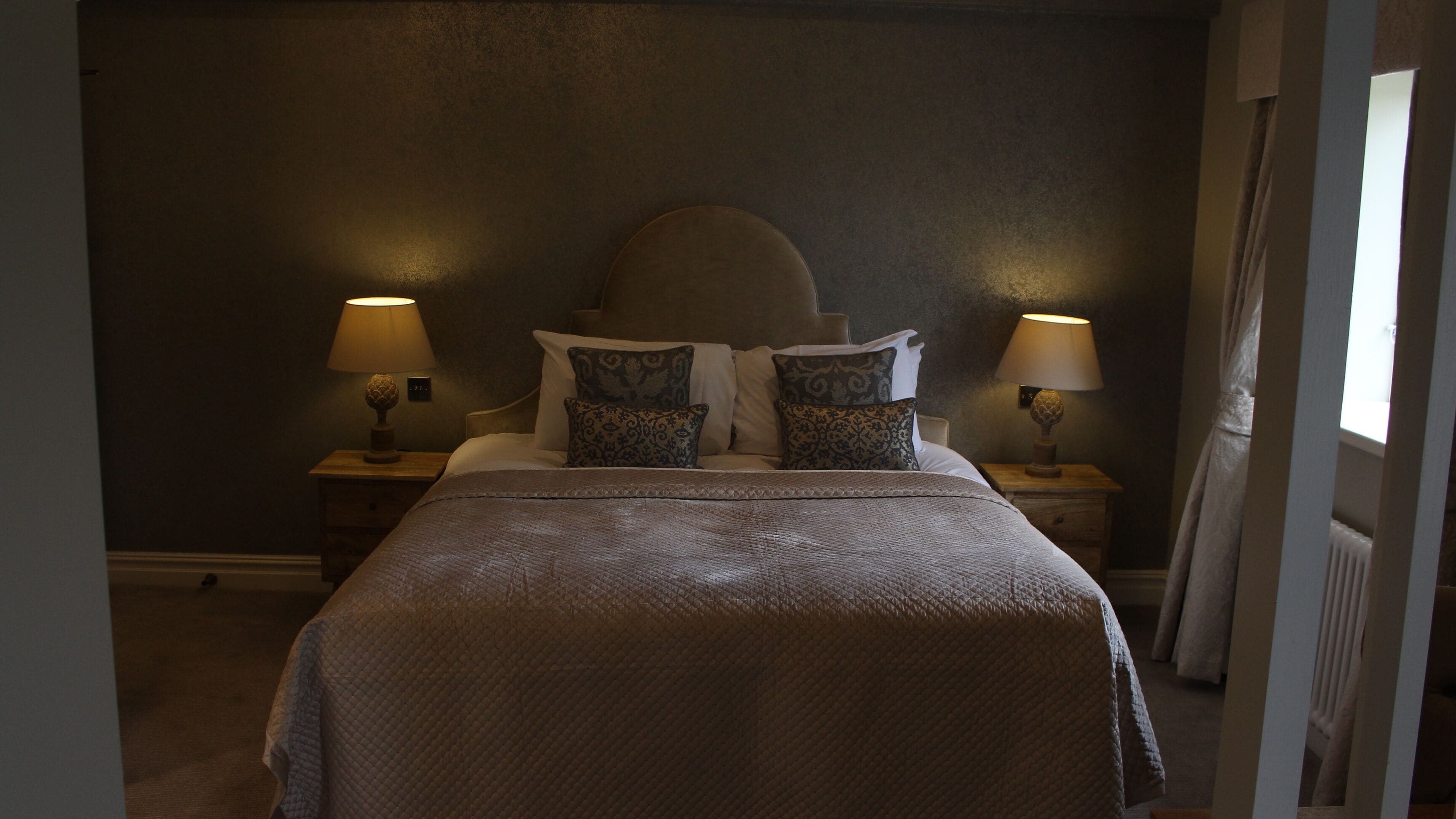 A neatly made bed with a textured blanket, two bedside tables with lamps, and a headboard.