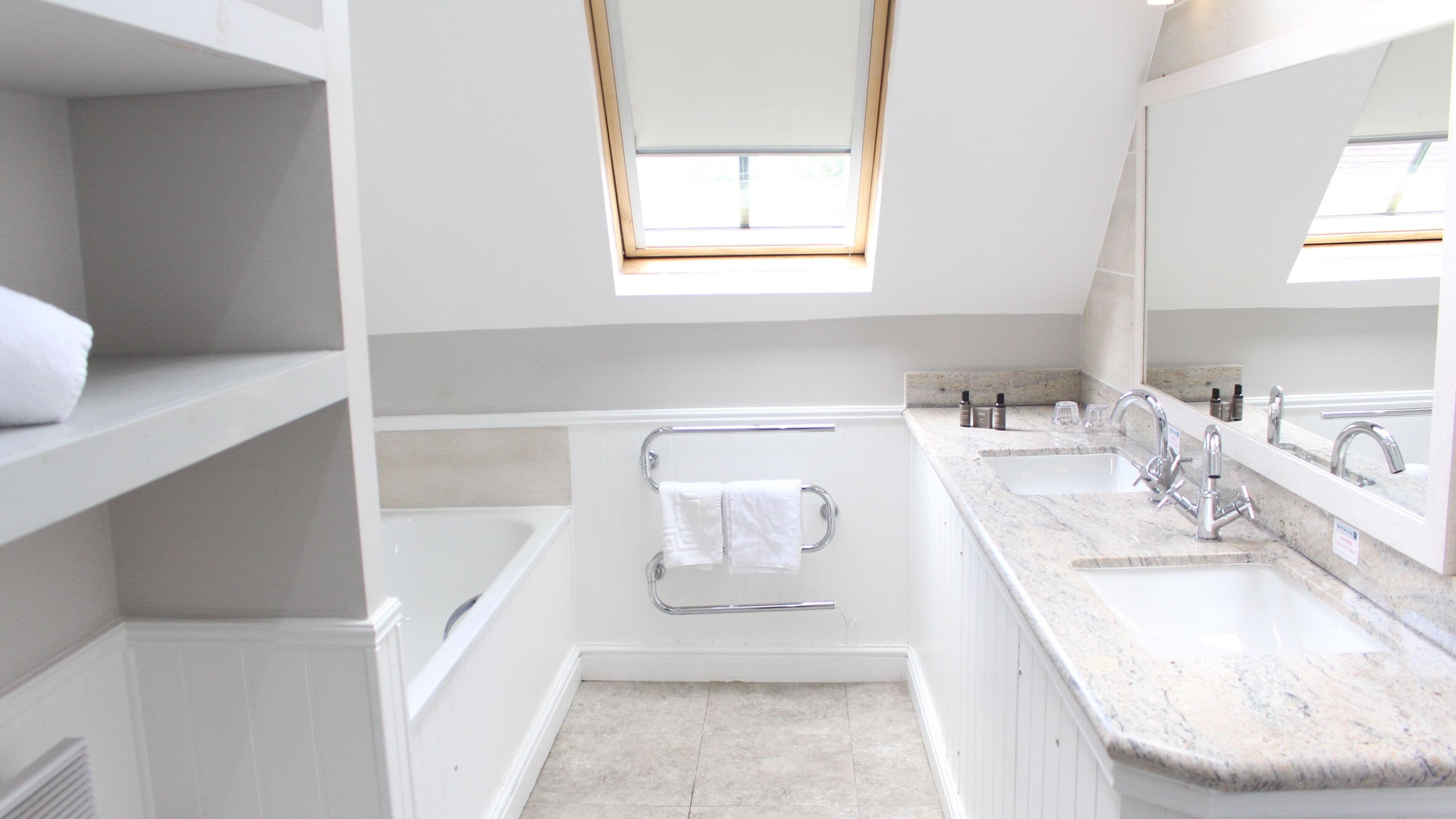 A modern bathroom with a large window, a bathtub, a shower, and a vanity with a sink and mirror.