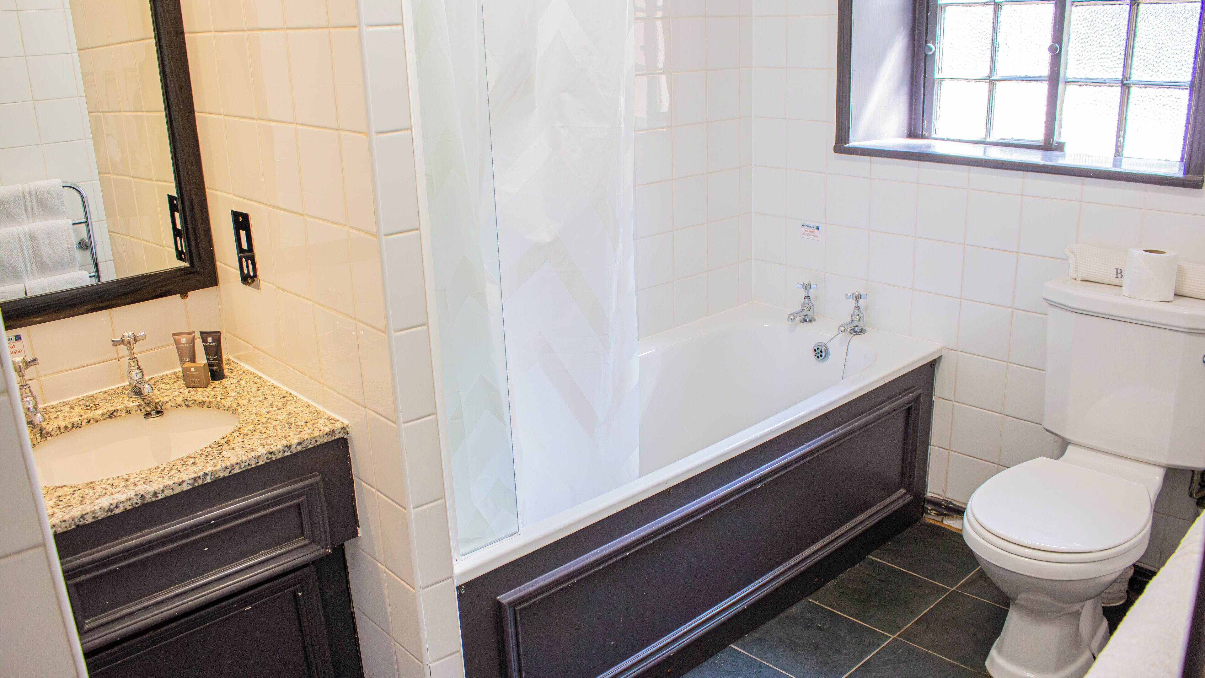 A bathroom with a sink, mirror, bathtub, and toilet.