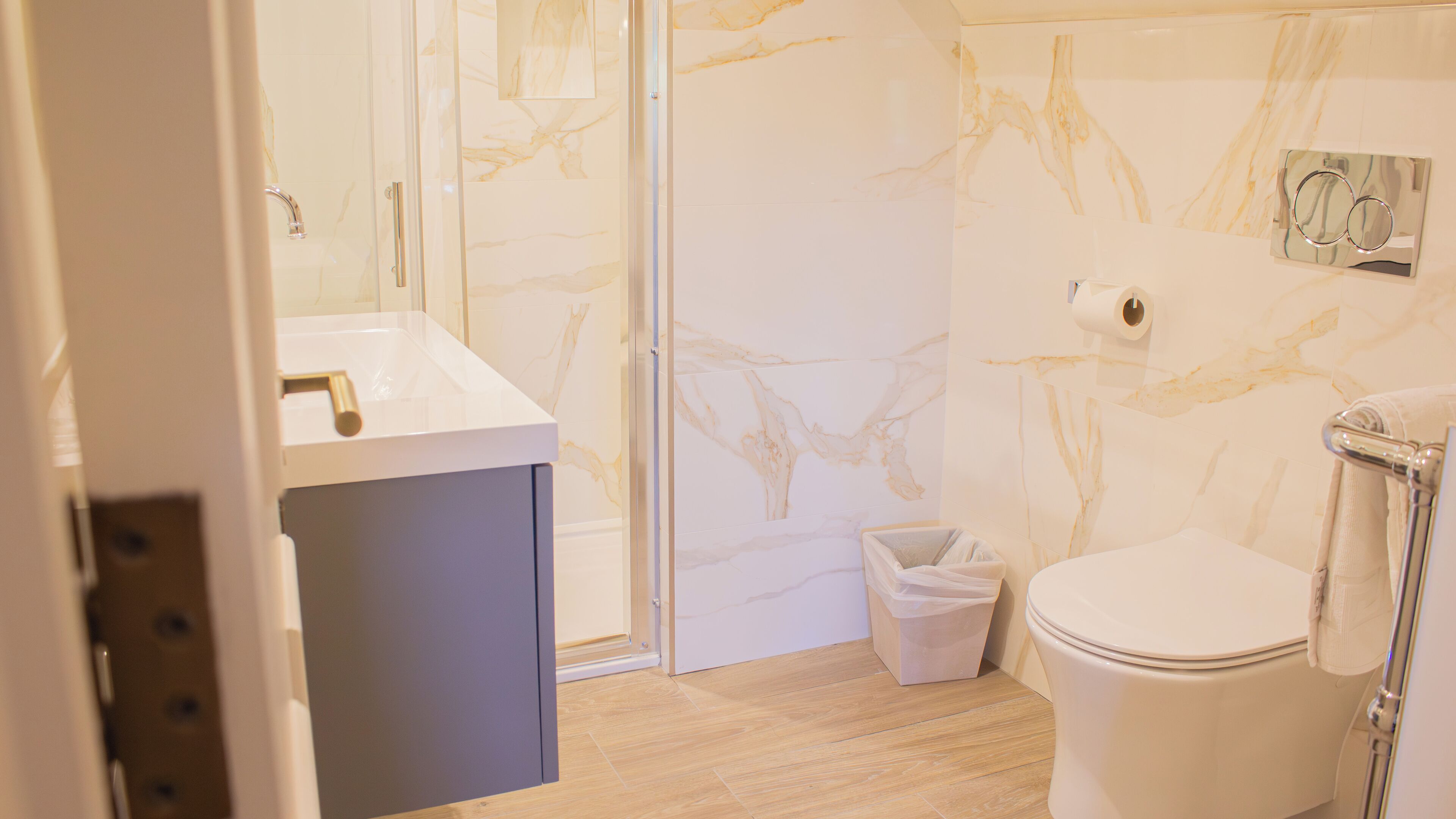A bathroom with a marble wall, a sink, and a toilet.