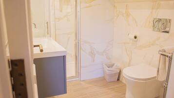A bathroom with a marble wall, a sink, and a toilet.
