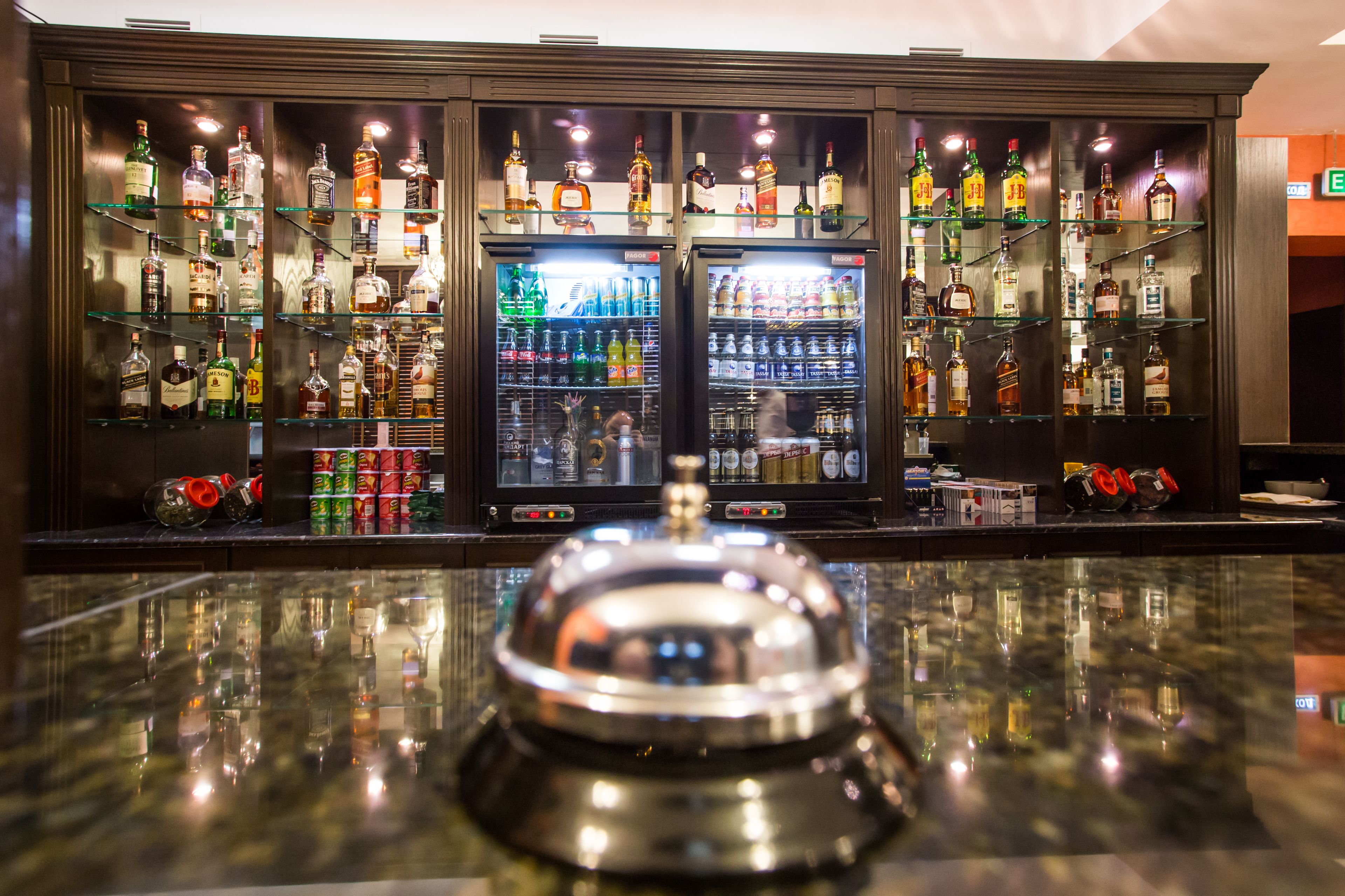 A bar area with shelves of liquor bottles and a large ice dispenser.