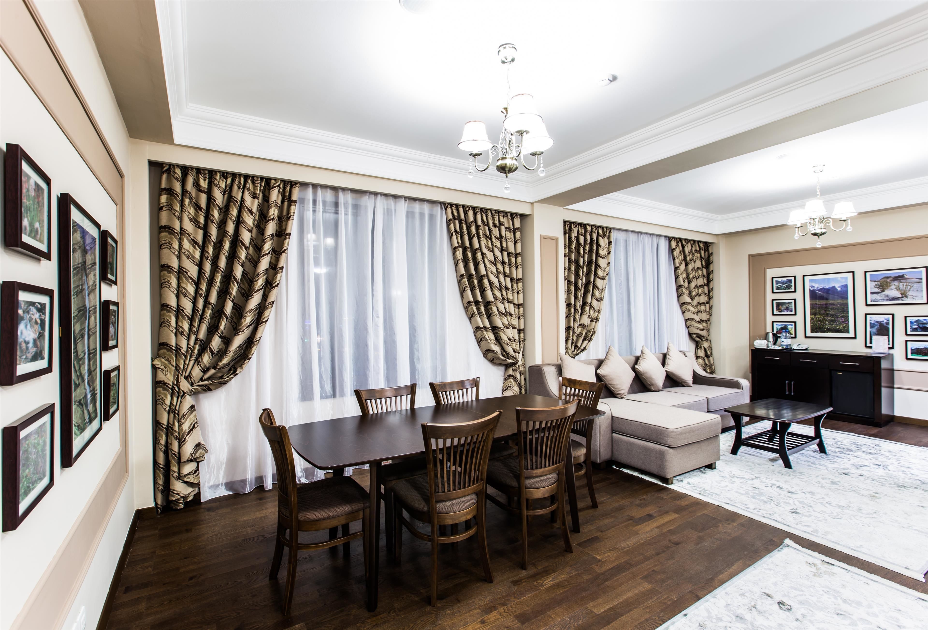 A dining area with a table and chairs, a sofa, and a chandelier.