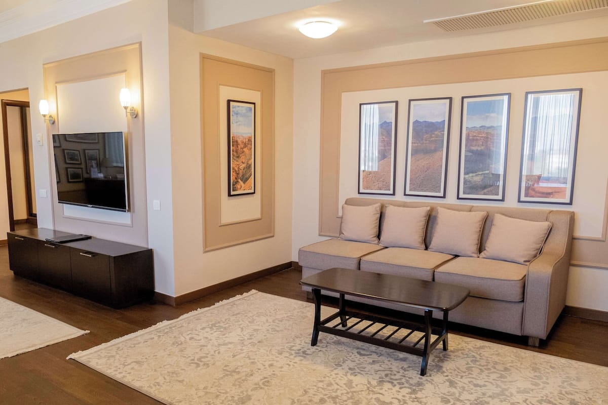 A living room with a sofa, a coffee table, a TV on a stand, and framed pictures on the wall.