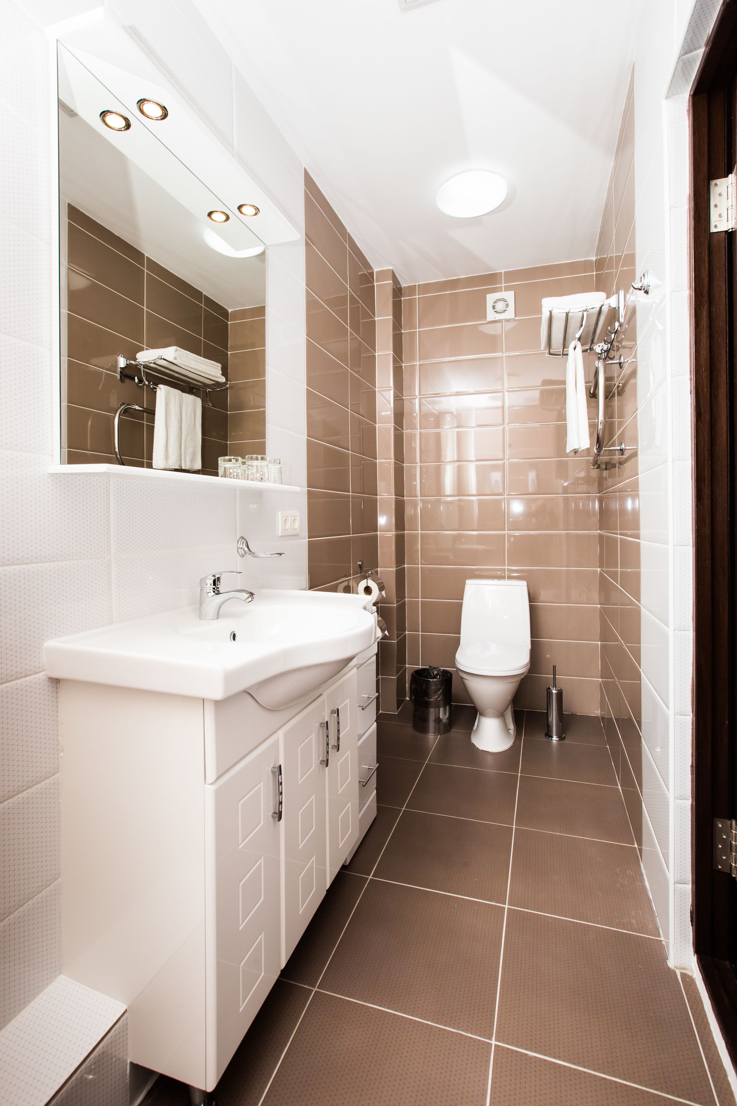 A modern bathroom with a white sink, mirror, and toilet.