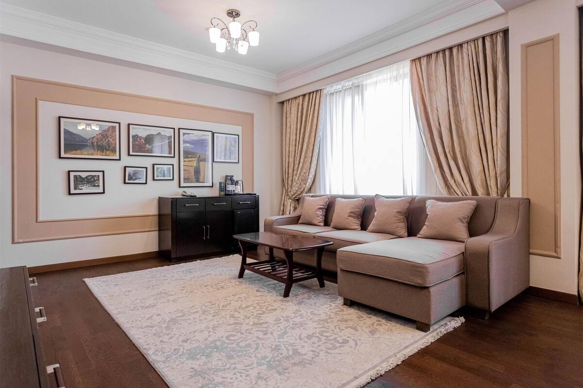 A living room with a sofa, a coffee table, a rug, and framed pictures on the wall.