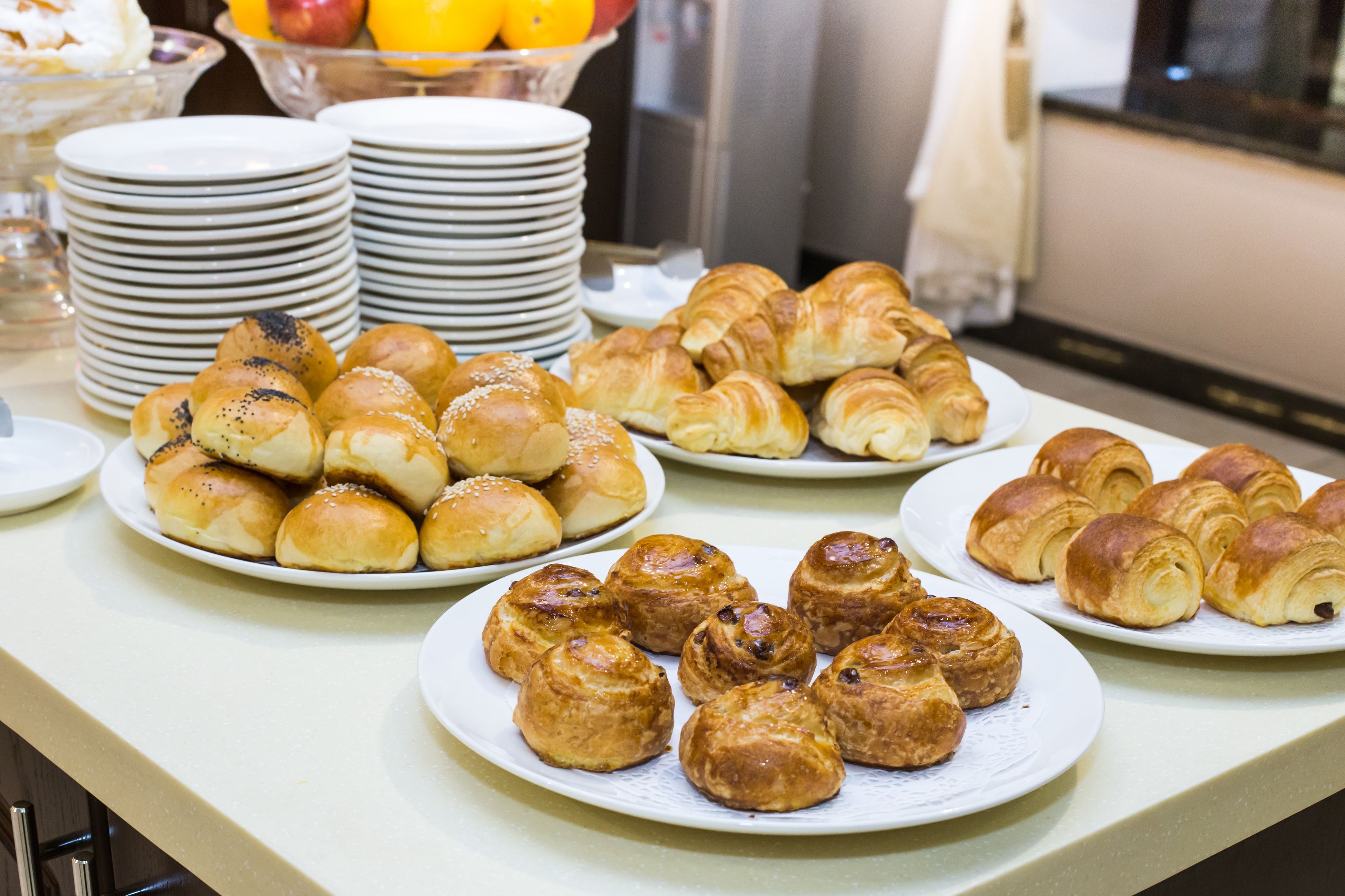 A buffet table with various pastries and plates of food.