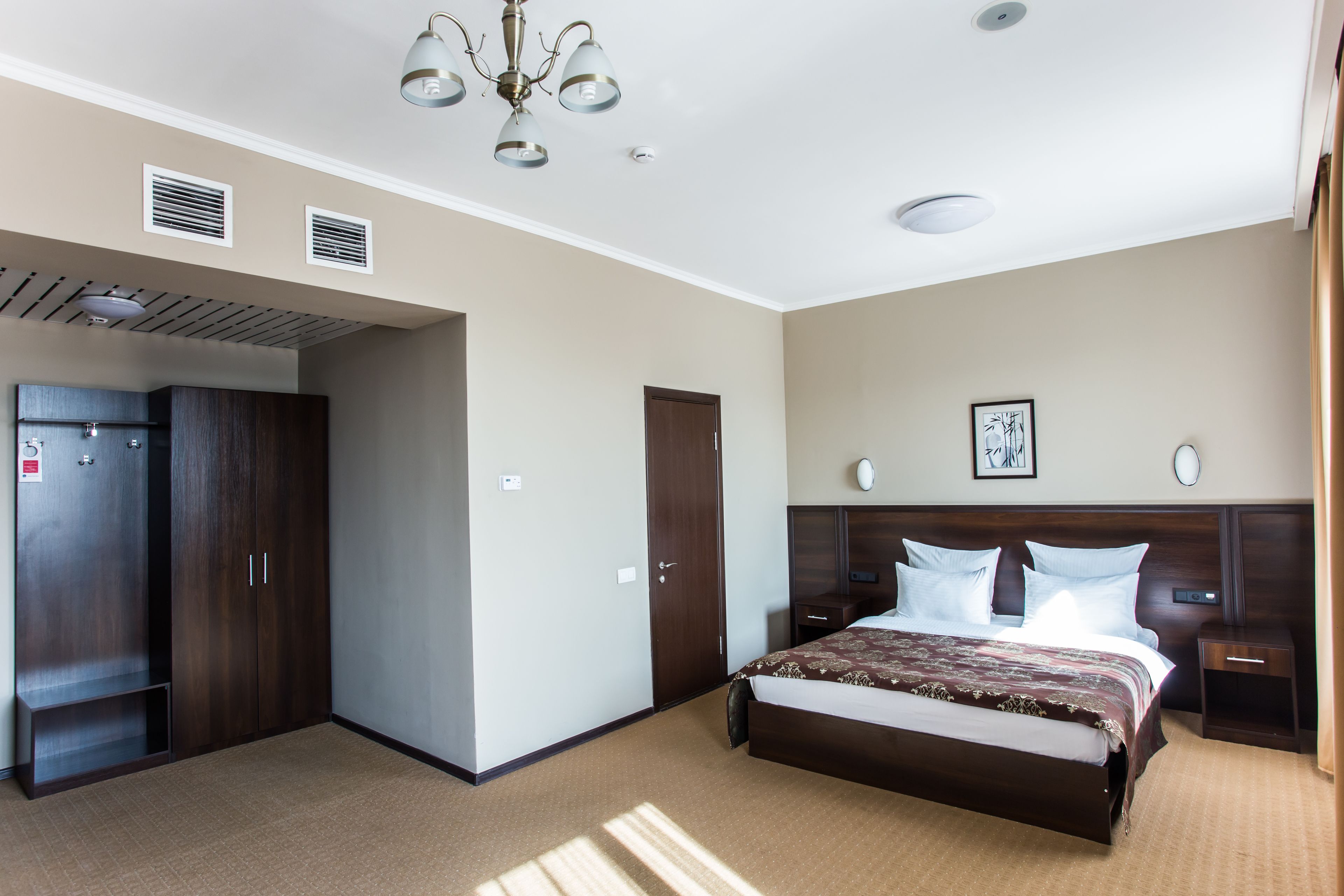 Een hotelkamer met een groot bed, een kledingkast, een bureau en een nachtkastje.