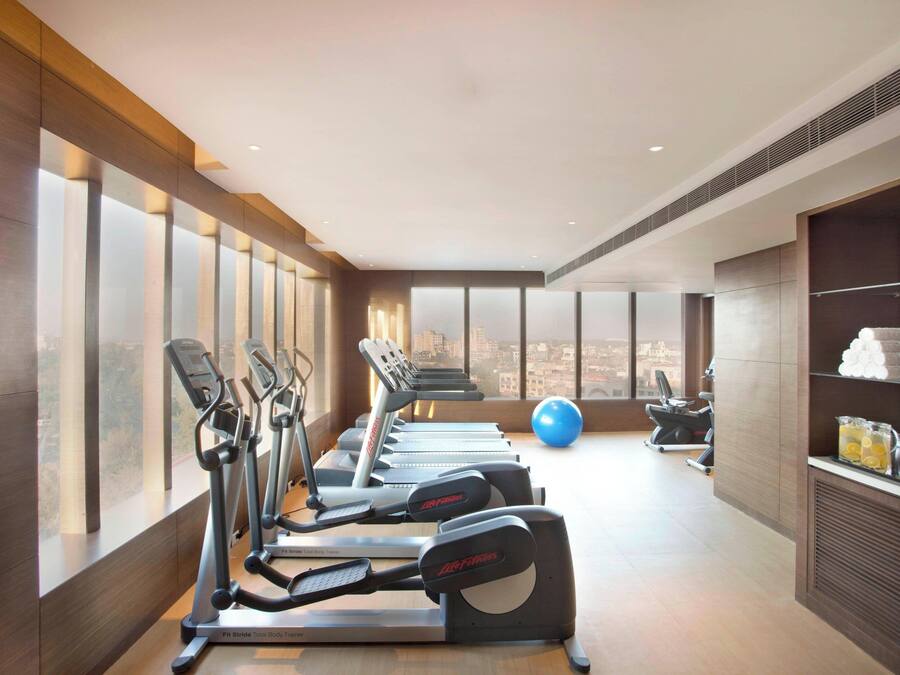 Un gimnasio con cintas de correr, una bicicleta estática y una pelota de ejercicios azul.