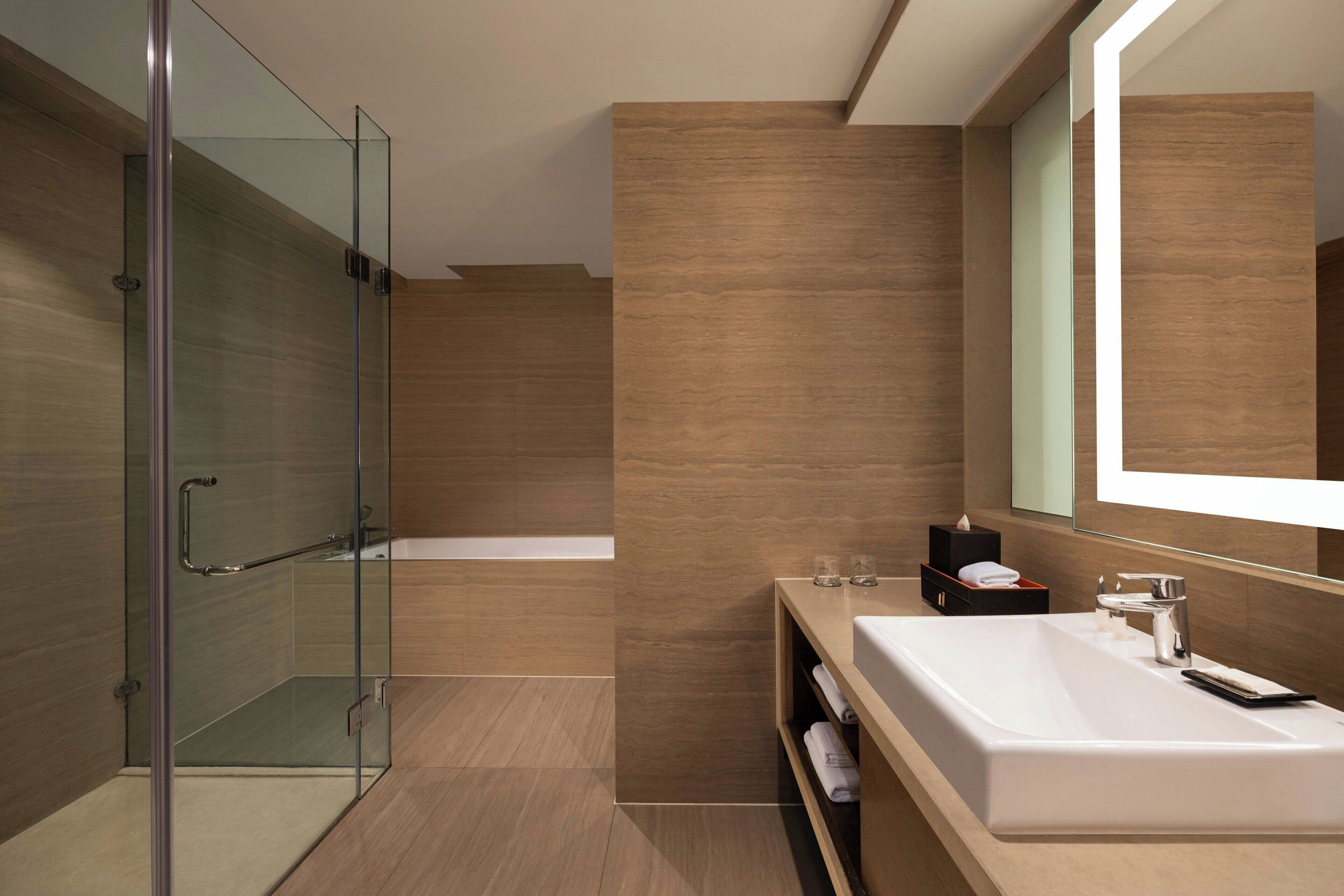 Un baño moderno con cabina de ducha de vidrio, un espejo grande y un lavabo blanco con tocador.