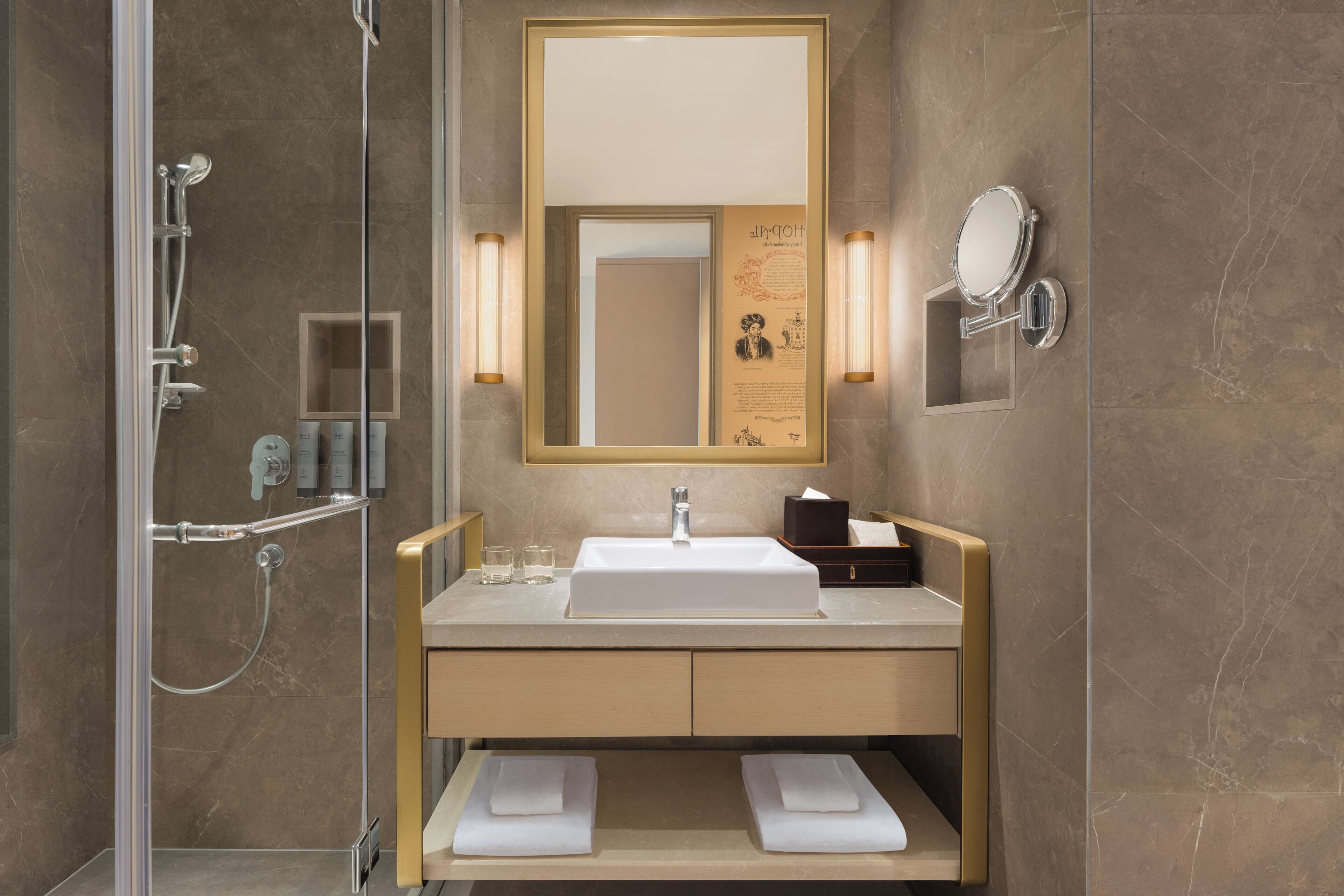 Une salle de bain moderne avec une douche à parois de verre, un lavabo avec un miroir et deux porte-serviettes.