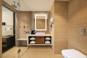 Een moderne badkamer met een douchecabine van glas, een ingebouwde wastafel met spiegel, en een toilet.