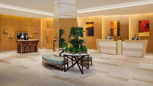 Um lobby moderno com balcão de recepção, área de estar e um grande pilar decorativo.