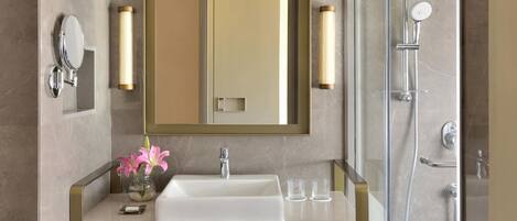 A modern bathroom with a vanity, mirror, and shower.