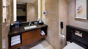A modern bathroom with a large mirror, a sink, a toilet, and a shower area.