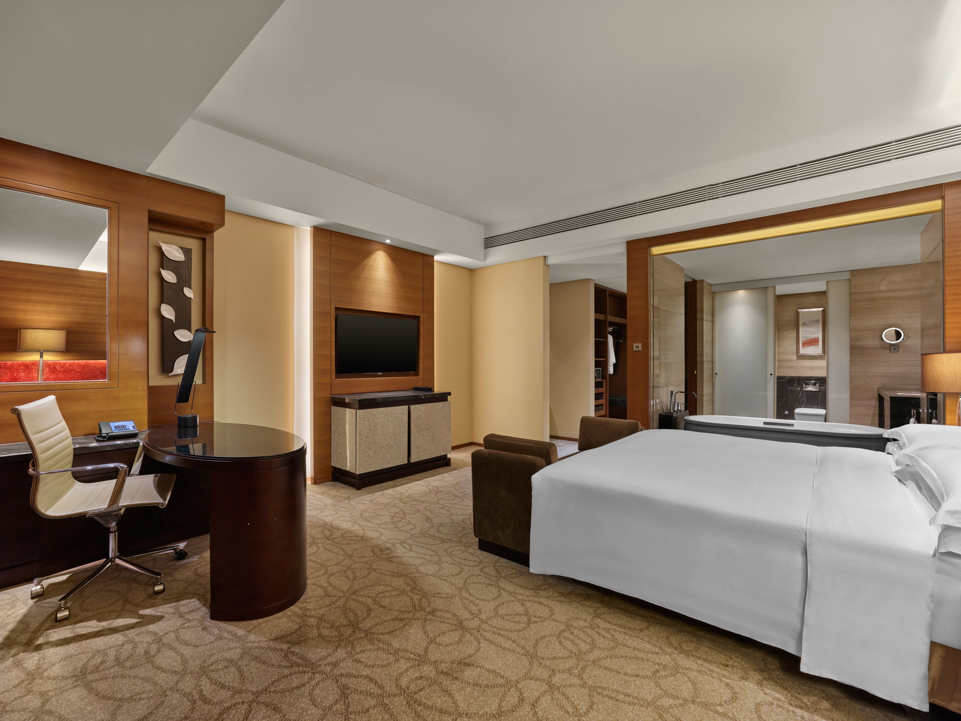 A hotel room with a bed, a desk, a chair, a television, and a bathroom.