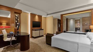 A hotel room with a bed, a desk, a chair, a television, and a bathroom.