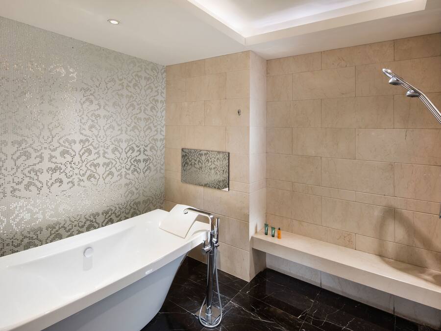 A modern bathroom with a freestanding bathtub, a showerhead, and a vanity with a mirror.