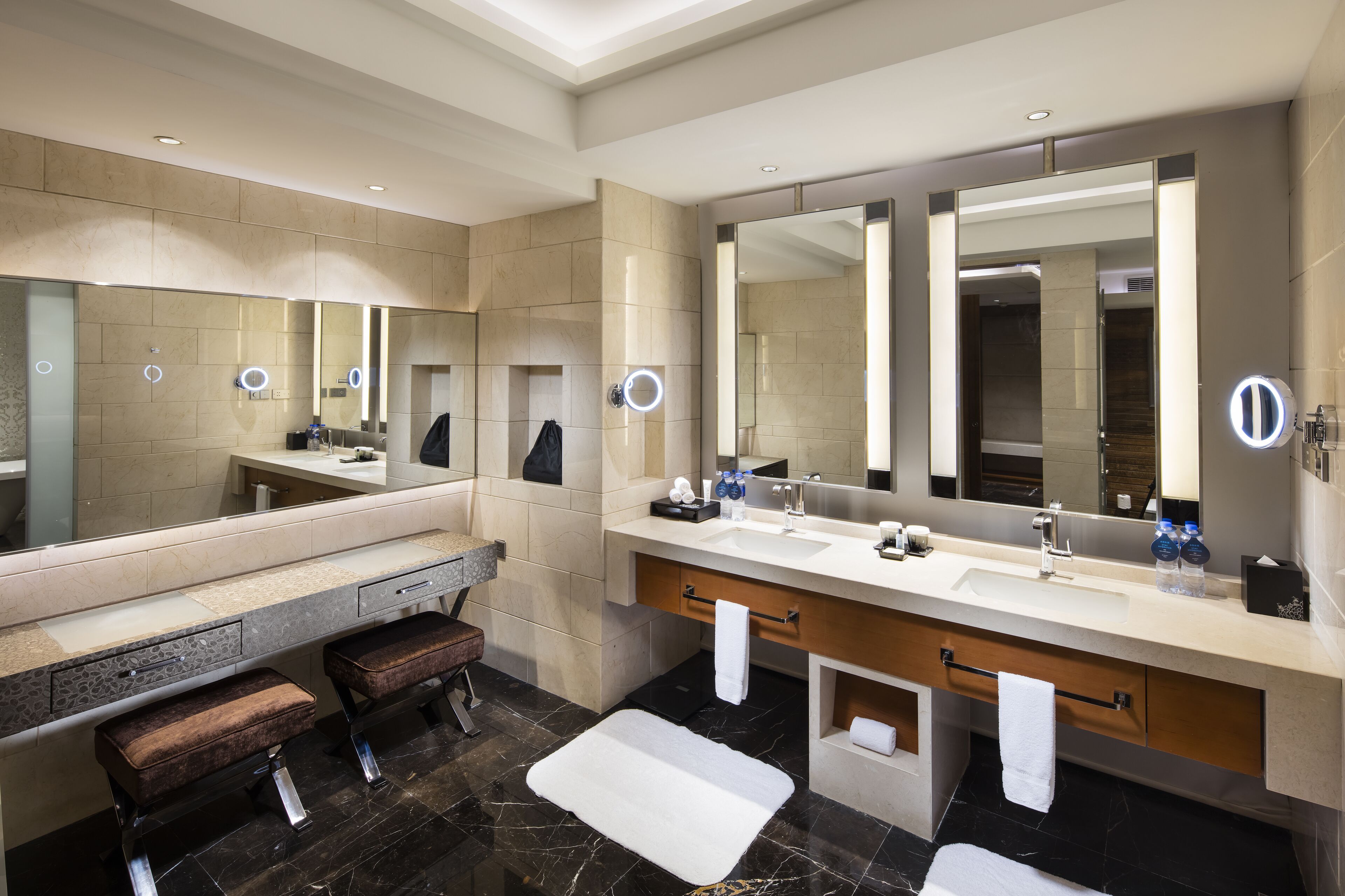 Een moderne badkamer met twee wastafels, grote spiegels en een bankje.