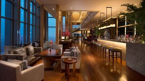 Un vestíbulo amplio con zona de bar, asientos y ventanas grandes.