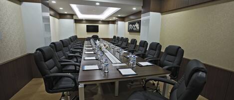 A conference room with a long table, black chairs, water bottles, and papers.
