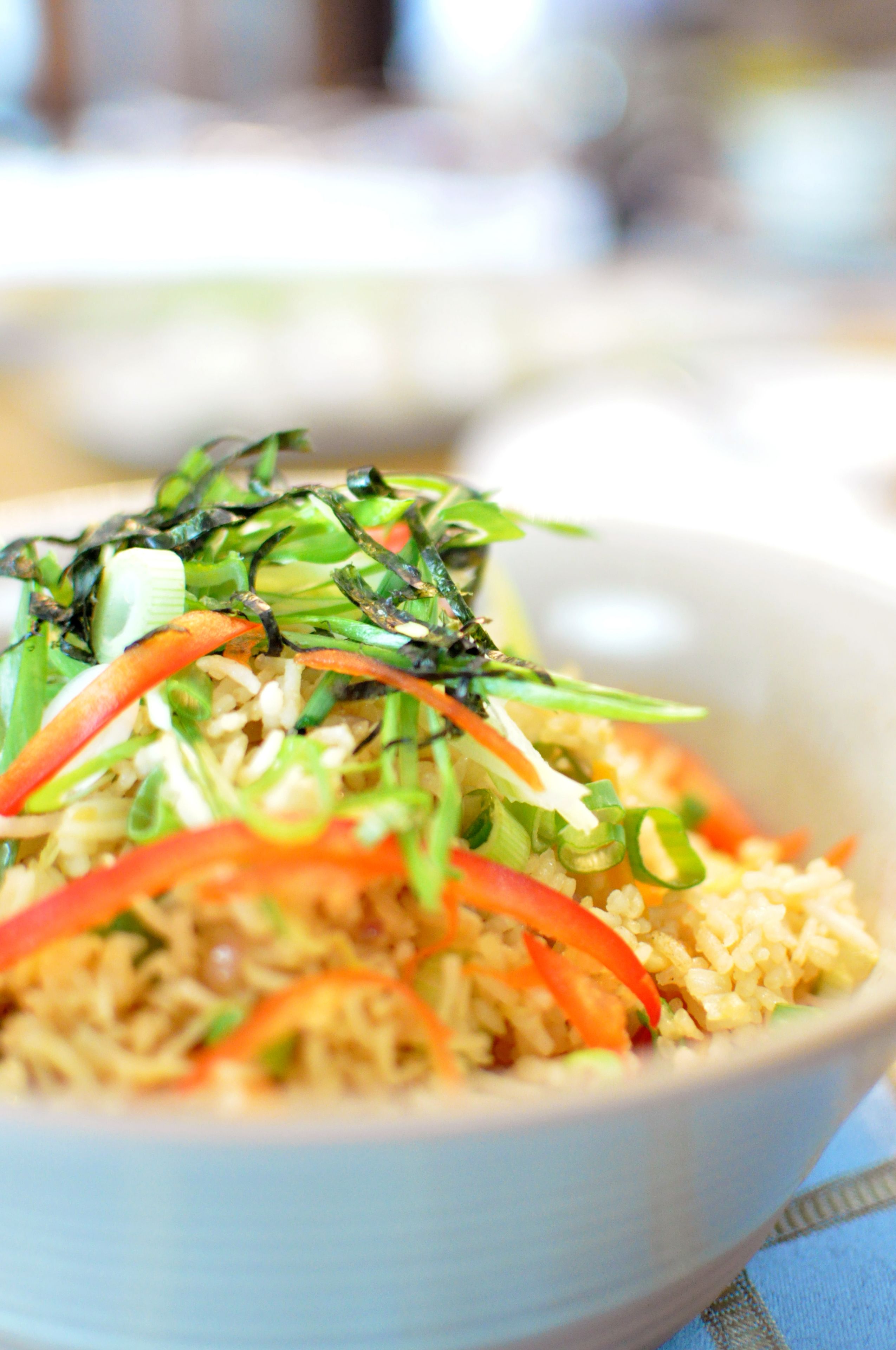 A bowl of rice with vegetables and seaweed.