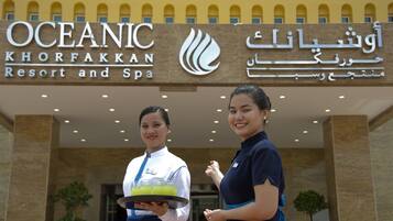 Placa do Oceanic Khorfakkan Resort and Spa com dois funcionários em frente.