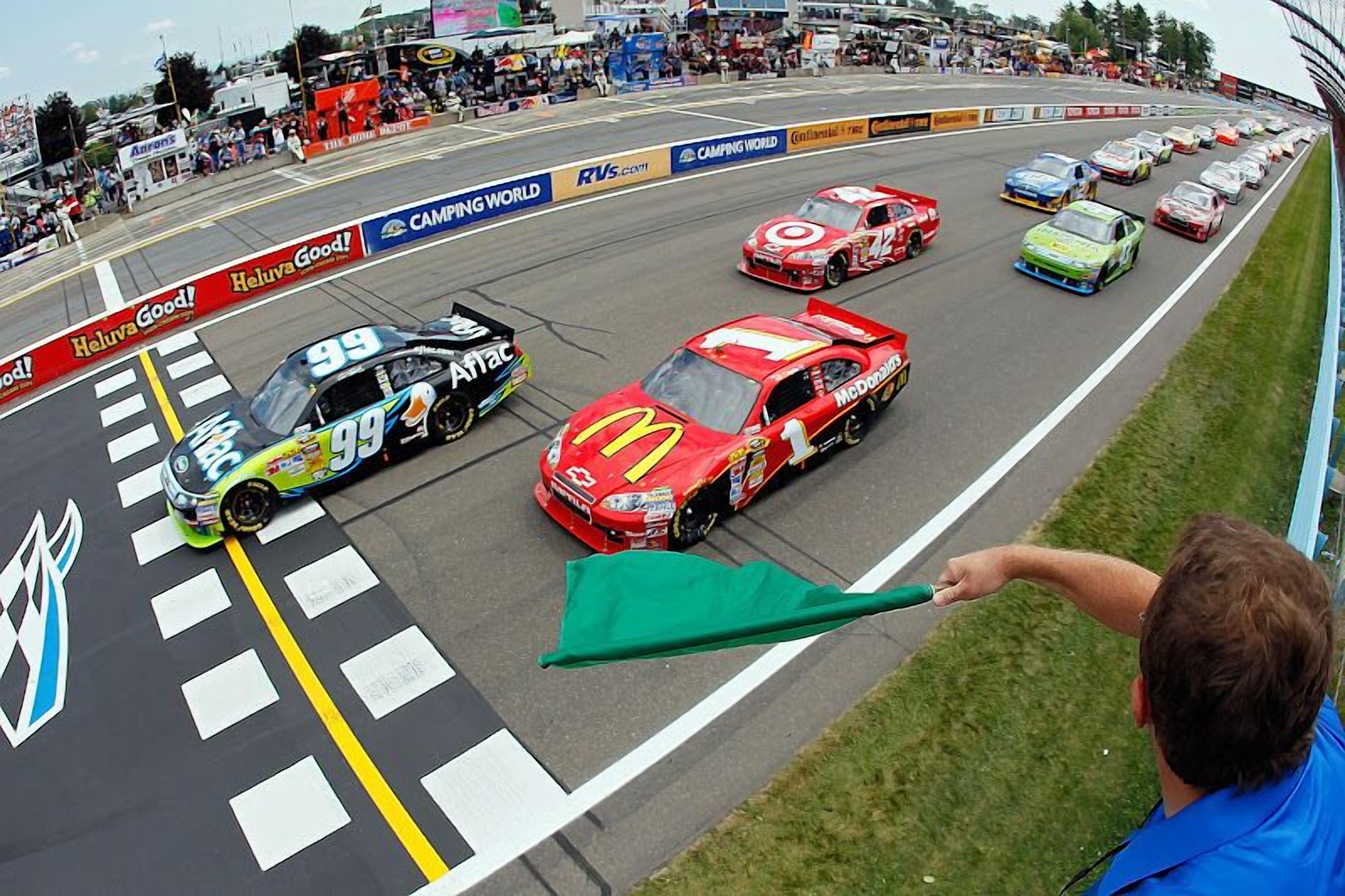 A race track with multiple racing cars and a crowd of spectators.