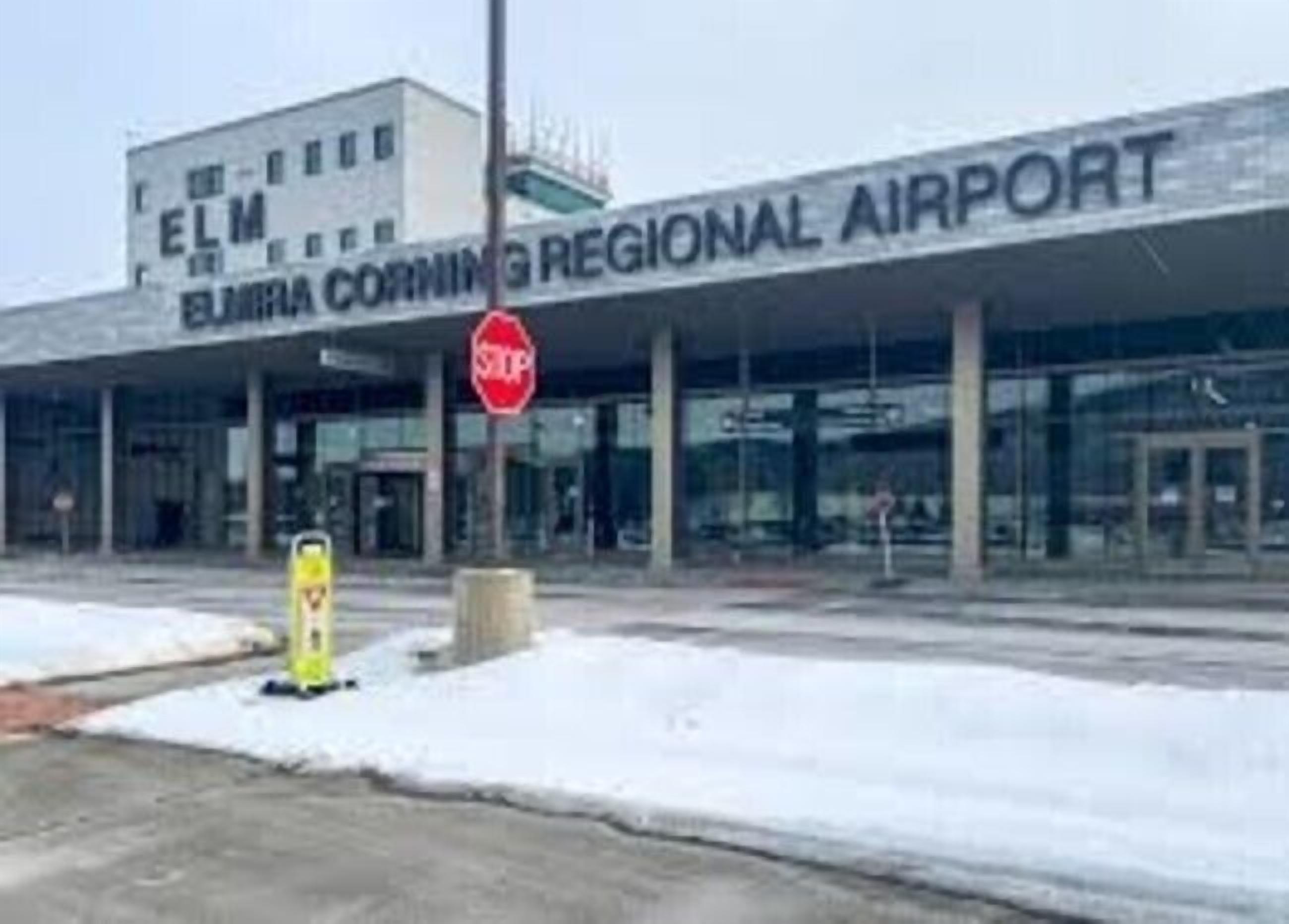 Terminal de aeropuerto con un letrero que dice 'ELM Regional Airport' y una señal de stop al frente.